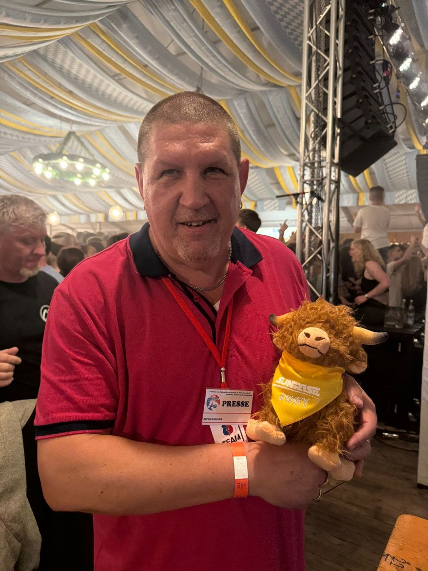 Juergen Schnabel hält das Sunrise-Maskottchen im Festzelt beim Heimattag der Siebenbürger Sachsen in Dinkelsbühl